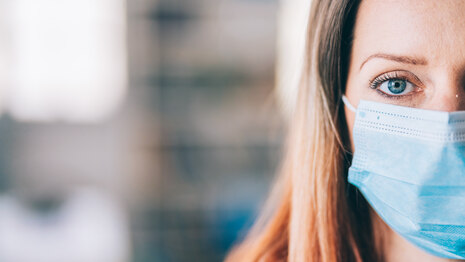 Frau trägt schützende Gesichtsmaske im Büro für Sicherheit und Schutz während COVID-19.